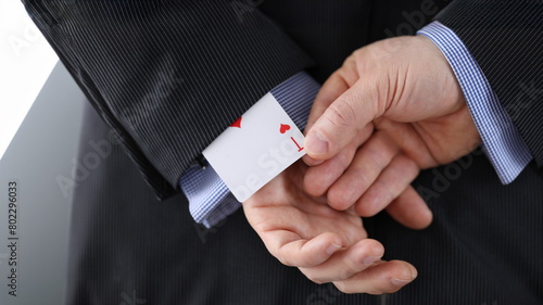Close-up of cheater hands pulling ace card out of sleeve with crossed arms behind. Gamer with strong addiction to games. Bribe casino and dishonesty concept