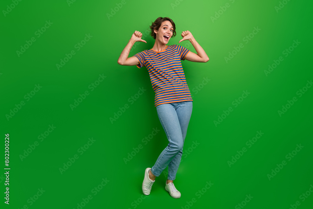 Full body portrait of crazy positive lady indicate thumb fingers self herself isolated on green color background Full body portrait of crazy positive lady indicate thumb fingers self herself isolated on green color background