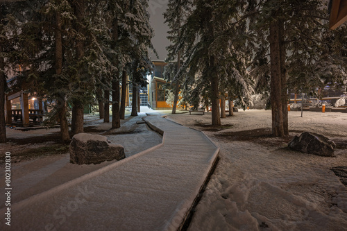 Night view of a snow-covered wooden walkway through Friendship Park in Canmore, Alberta, Canada