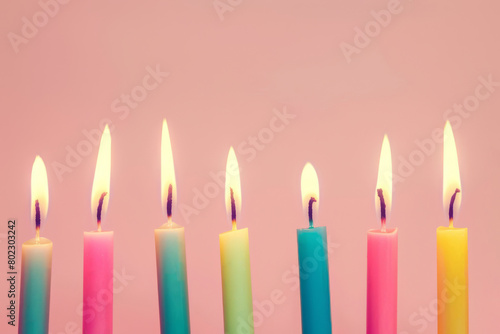 A row of colorful candles with a pink background
