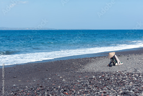 Older women collect small pebbles from the ground Kusamba beach in Bali Indonesia. photo