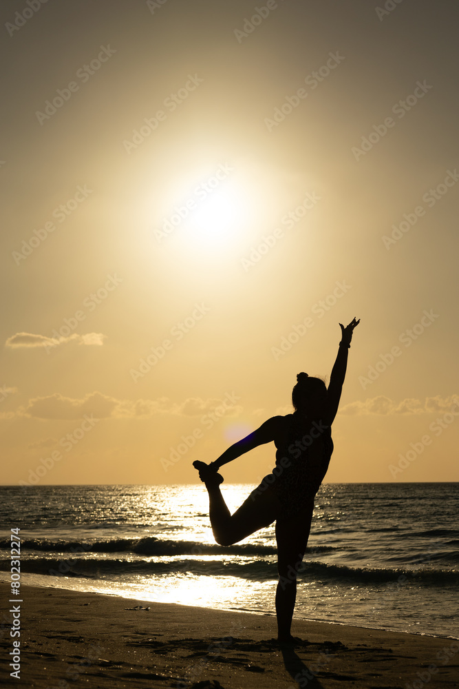 Fototapeta premium photo of muscular woman silhouette against light at sunset on the Cuban Caribbean doing yoga