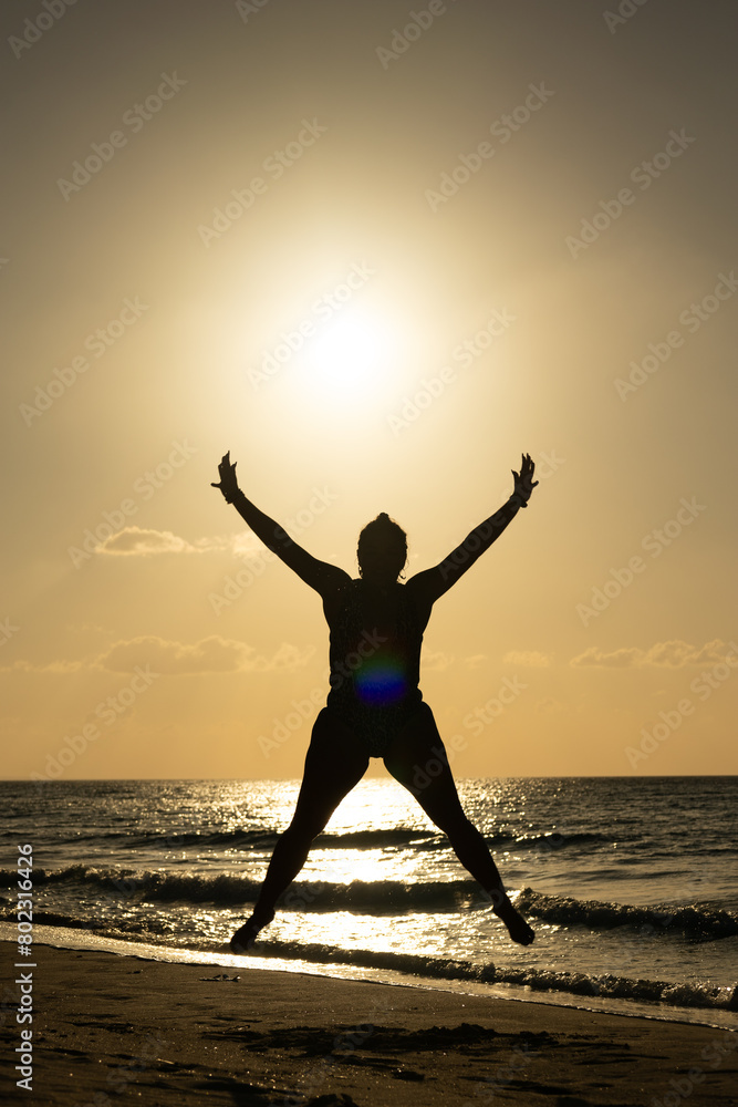 photo of muscular woman silhouette against light at sunset on the Cuban Caribbean jumping