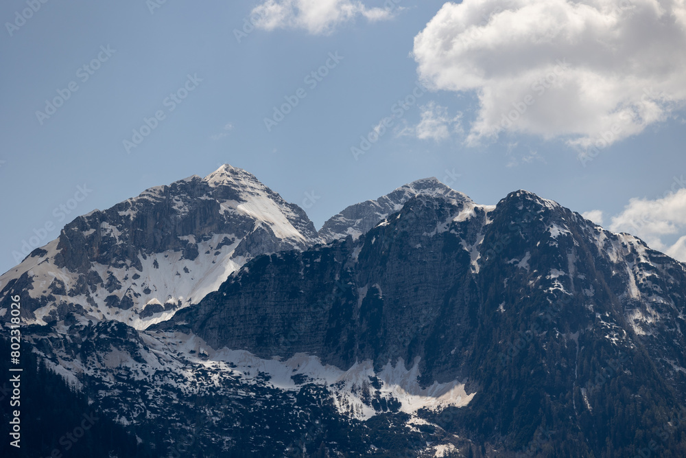 View of mountains in the Alps with splotches of snow on the peaks on a sunny day.