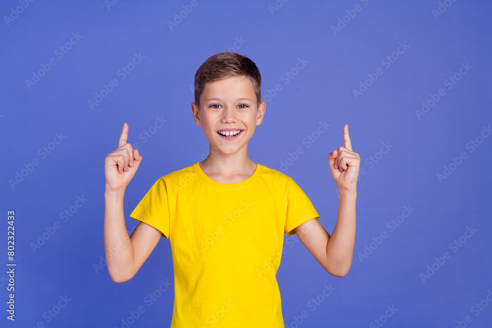 Photo of cheerful cute small boy wear trendy yellow clothes recommend novelty empty space isolated on purple color background Photo of cheerful cute small boy wear trendy yellow clothes recommend novelty empty space isolated on purple color background