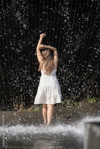 woman standing barefoot in falling water fountain photo