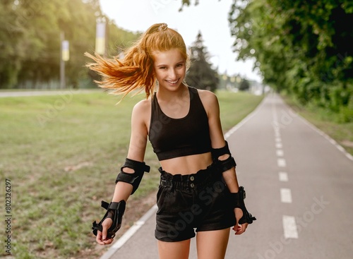 Teenage girl in sportswear enjoying roller skating in summer park