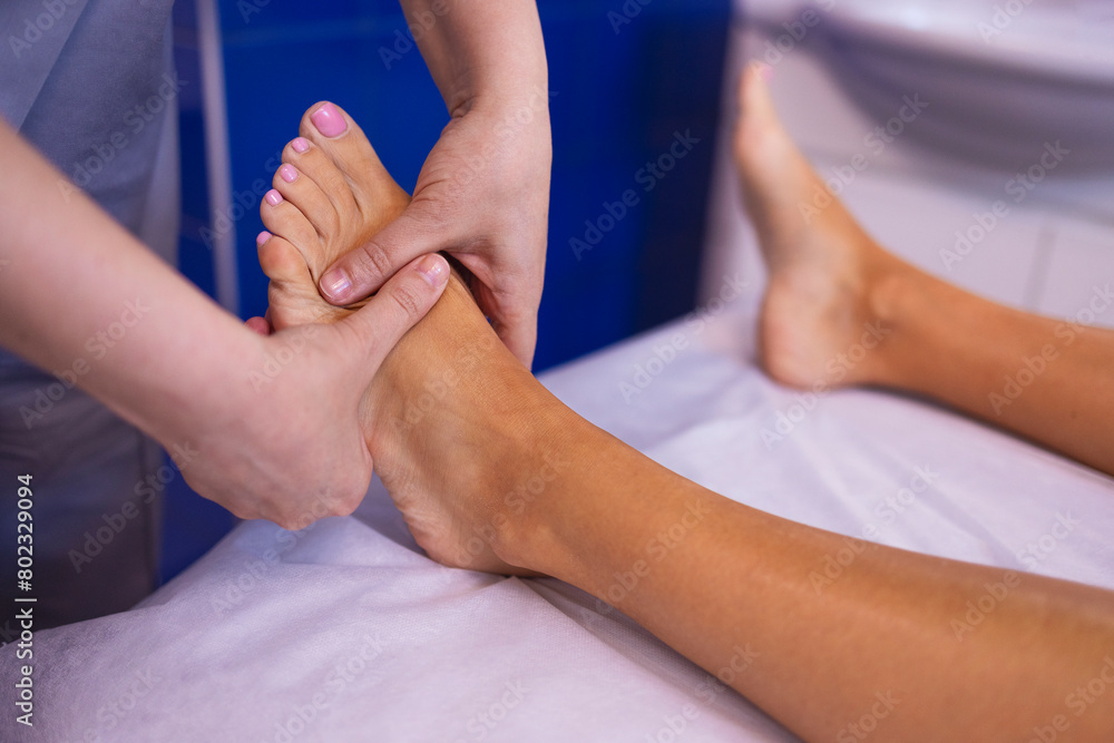 Close up of female foot getting gentle massage. Masseuse holds woman leg in her hands. Young client lies and enjoys relaxing procedure in beauty salon. Spa treatment. Yourself and skincare. Copy spase