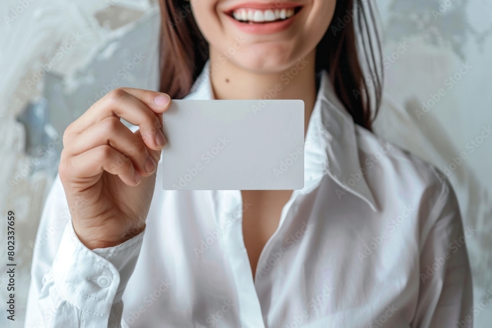 A woman is smiling and holding up her empty/ white color business card, wearing a white shirt in a professional, white background A woman is smiling and holding up her empty/ white color business card, wearing a white shirt in a professional, white background