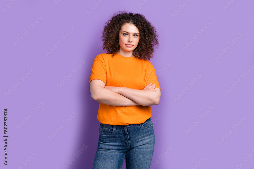 Photo of serious confident woman wear orange t-shirt arms folded isolated purple color background Photo of serious confident woman wear orange t-shirt arms folded isolated purple color background