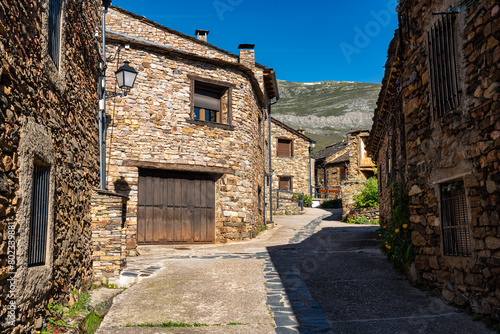 Narrow picturesque alley with stone houses next to the mountains of central Spain. © josemiguelsangar