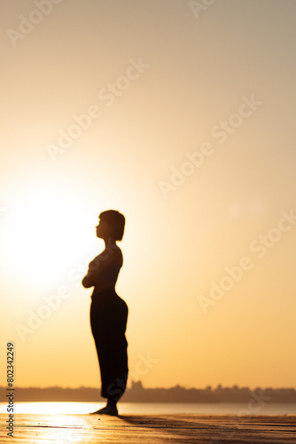 blurred silhouette image of a girl doing yoga at dawn