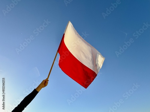 Polska flaga biało-czerwona powiewająca na wietrze na tle błękitnego nieba. Dzień Flagi, Święta Narodowe, 3 Maja, patriotyzm. © Anita