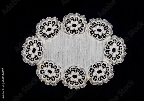 Vintage handmade white knitted napkin isolated on a black background.