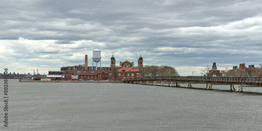 ellis island view with bridge and hudson river (from liberty state park in jersey city nj) new immigrant arrival museum historical site dark dramatic sky cloudy (york history immigration europe)