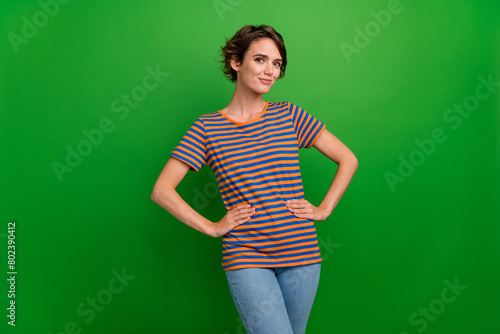 Portrait of satisfied stunning girl put hands waist posing good mood isolated on green color background © deagreez