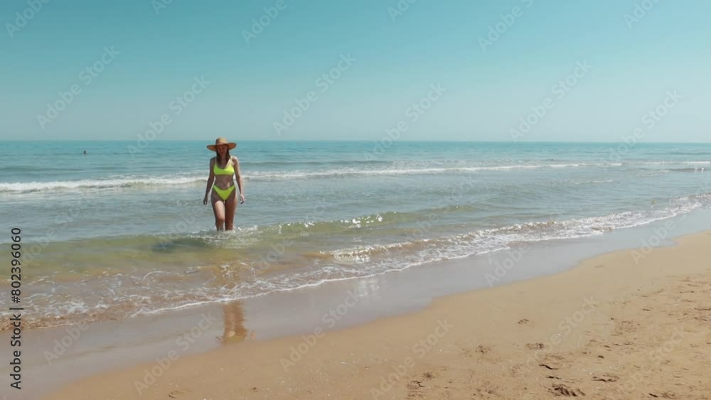 Happy young girl in hat and swimsuit walks along beach. holiday at sea. Beautiful sun light on coast. Happy young girl in hat and swimsuit walks along beach. holiday at sea. Beautiful sun light on coast.