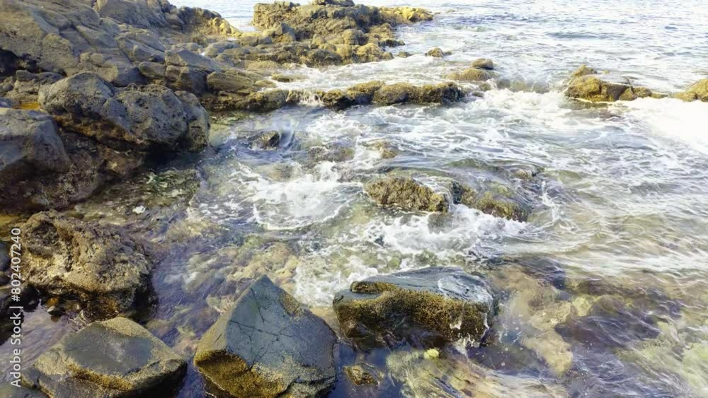 clear water of the Atlantic Ocean washing the rocky coast. It is visible on the bottom of the colored stones clear water of the Atlantic Ocean washing the rocky coast. It is visible on the bottom of the colored stones