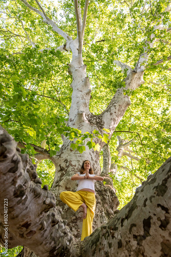 Beautiful woman with gorgeous curly hair doing yoga in nature  dressed in white and yellow combination  concept  active healthy life  in love with nature  support  balance  wellbeing  energy