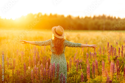 Beautiful woman holding bouquet of lavender flowers walking in summer meadow. Fashion, beauty, nature concept. Collection of medicinal herbs.