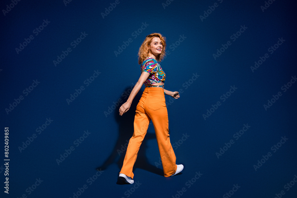 Full body rear profile portrait of nice young lady walk empty space wear top isolated on dark blue color background Full body rear profile portrait of nice young lady walk empty space wear top isolated on dark blue color background
