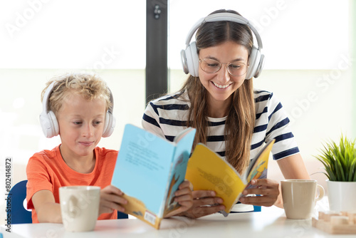 A mother and her son real childrens's books, while listening to music with their white headphones