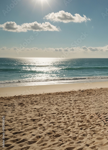 Sunny beach with sparkling ocean and footprints