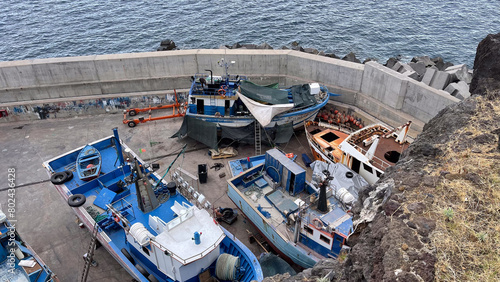 Fishing boats undergoing maintenance in a small harbor area at Câmara de Lobos, Madeira photo