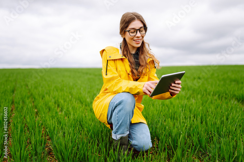 Woman Farmer on a green wheat field with a tablet. Smart farm. The concept of the agricultural business © maxbelchenko