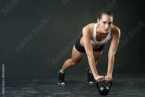 Fitness, kettle bell and space with sports woman in studio on dark background for physical workout. Exercise, mindset and weights with serious athlete training body in health club for challenge