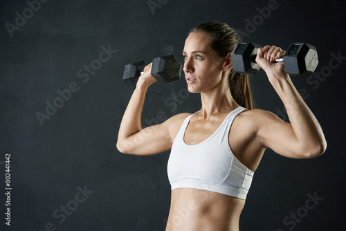 Fitness, body or woman with dumbbells in studio for exercise, training or muscle transformation or challenge on black background. Gym, sport or athlete with weightlifting action, wellness or progress