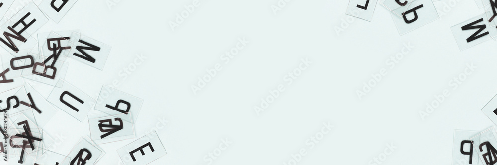 Transparent plastic cards with letters scattered on a blue background. Banner with copy space. Transparent plastic cards with letters scattered on a blue background. Banner with copy space.