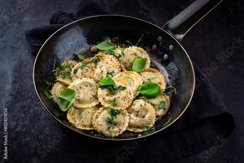 Traditional Italian medaglioni pasta staffed with parmesan cheese and pesto served as close-up in a rustic frying pan with copy space photo