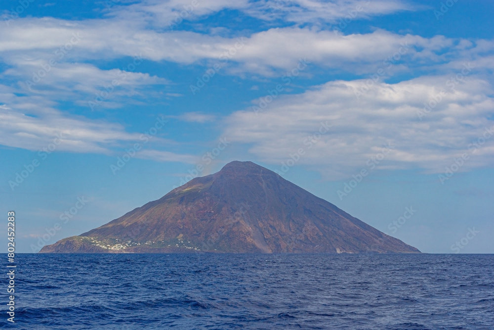 Salina island against the sea water and blue cloudy sky. Sea view from the sailing boat of a volcanic island in Aeolian archipelago in the Tyrrhenian Sea. Salina, Aeolian islands, Italy Salina island against the sea water and blue cloudy sky. Sea view from the sailing boat of a volcanic island in Aeolian archipelago in the Tyrrhenian Sea. Salina, Aeolian islands, Italy