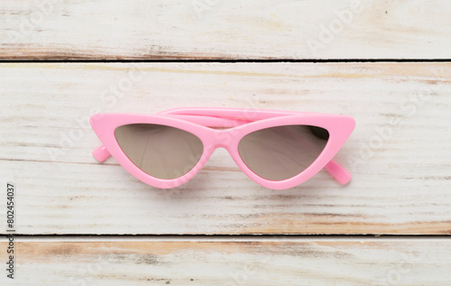 Stylish yellow sunglasses on wooden background, top view. Summer concept