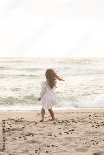 Little girl with white dress running in the beach during sunset in Lima Peru 
