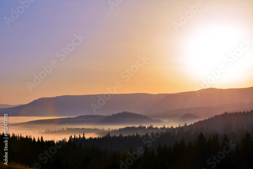Beautiful landscape with a sunrise over the mountains with fog in the valley © sebi_2569