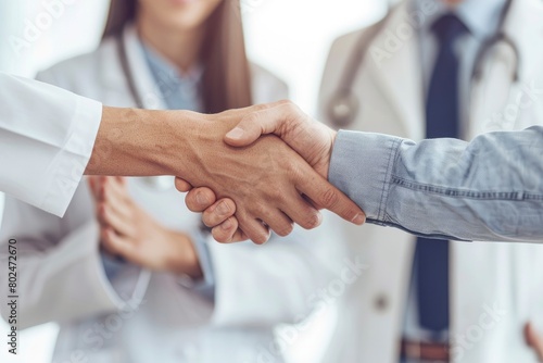 Doctor shaking hands with his patient while the nurse is smiling in front of them photo