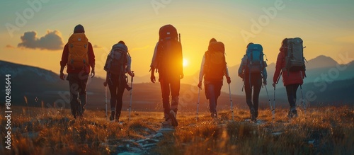 mountain climber with bag and stick at the top of the mountain during sunset photo