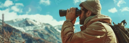 Man looking through binoculars, naturalist, spy, wildlife observation outdoors on sunny day photo
