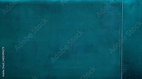 A close-up texture shot of teal-colored leather material with a visible seam line photo