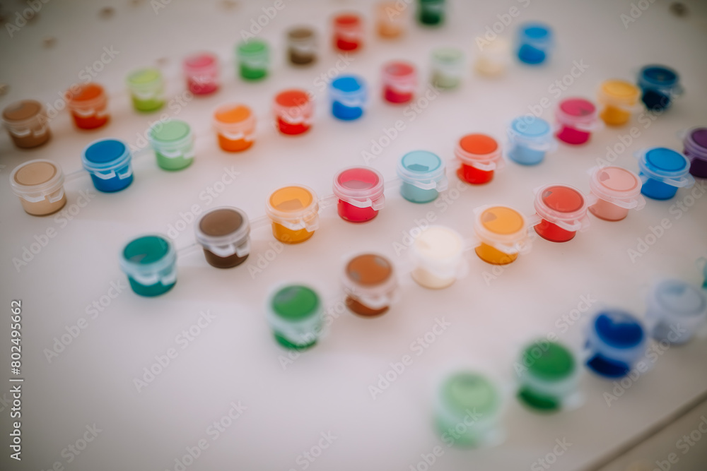 Valmiera, Latvia - August 19, 2023 - Arranged open paint pots in various colors are displayed on a white surface, showing a vibrant array of choices for art and craft. Valmiera, Latvia - August 19, 2023 - Arranged open paint pots in various colors are displayed on a white surface, showing a vibrant array of choices for art and craft.