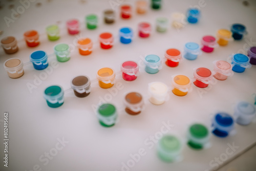 Valmiera, Latvia - August 19, 2023 - Arranged open paint pots in various colors are displayed on a white surface, showing a vibrant array of choices for art and craft.