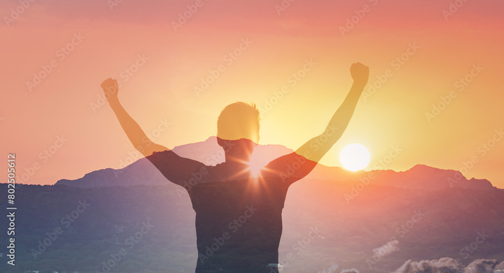 Hiker with arms raised on a mountain facing beautiful sunset silhouette against golden sky.	
