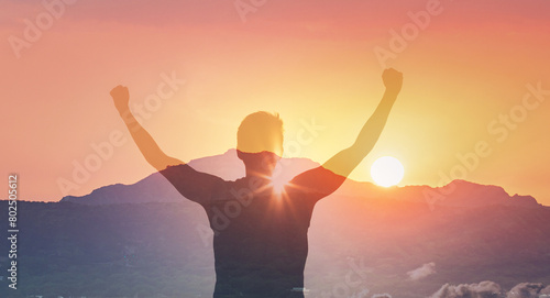 Hiker with arms raised on a mountain facing beautiful sunset silhouette against golden sky.  © kieferpix