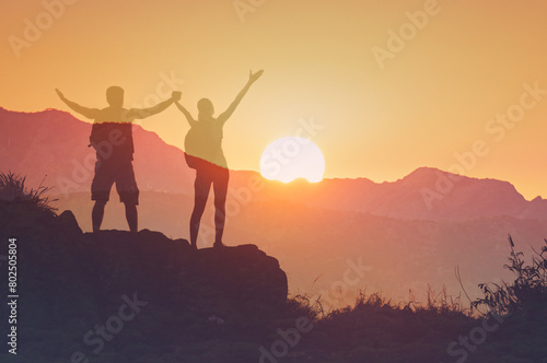 silhouette  young man and woman celebrating victory looking out to the mountain sunrise   