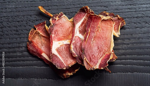 macro photo of dried sliced lamb meat on black wooden surface top view