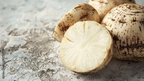 A close-up of a fresh organic yucca root, its rough exterior and white interior displayed on a light background to highlight its starchy texture, with space for text photo