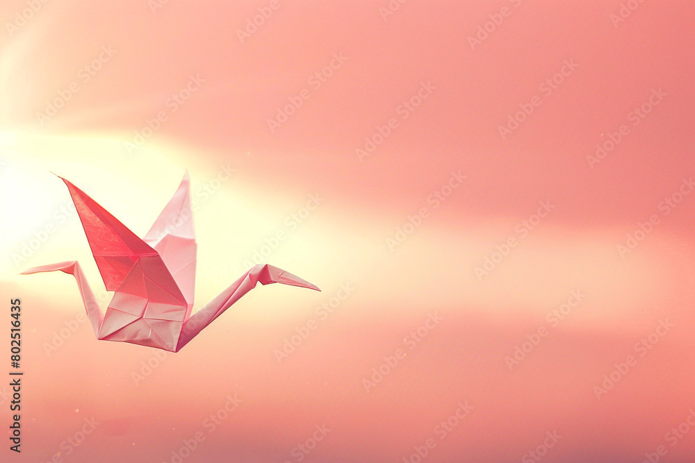 Naklejka premium A pink paper crane floating in the air against a pink sky.