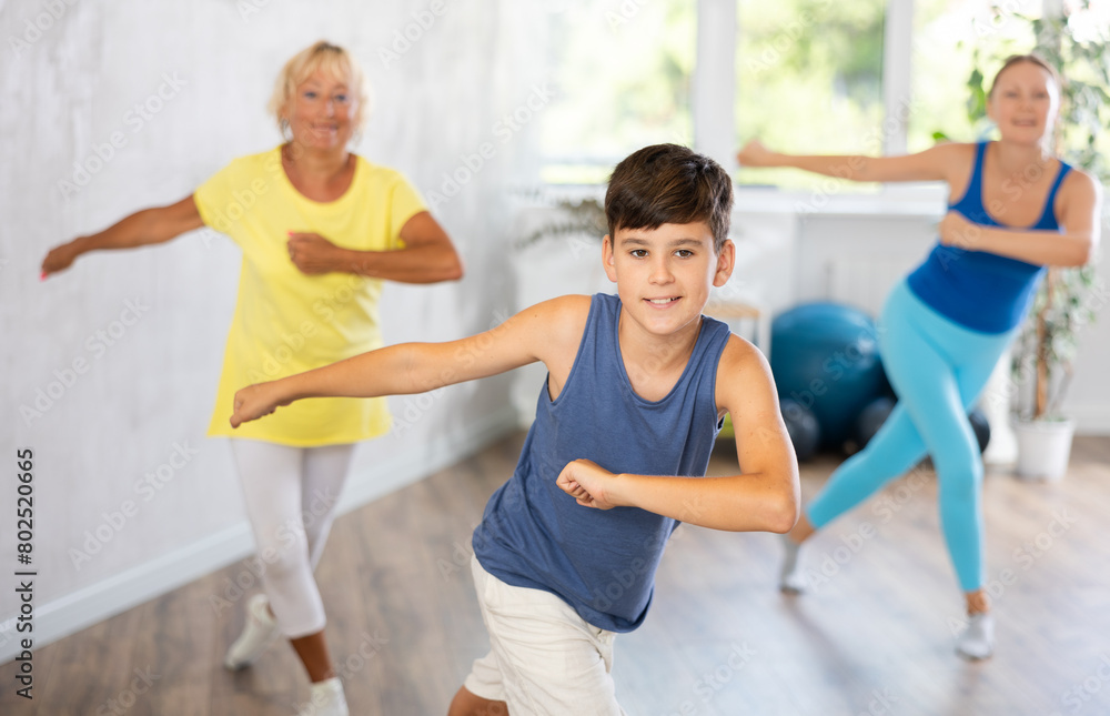 Fototapeta premium Family of three is actively moving while performing dance fitness exercises.